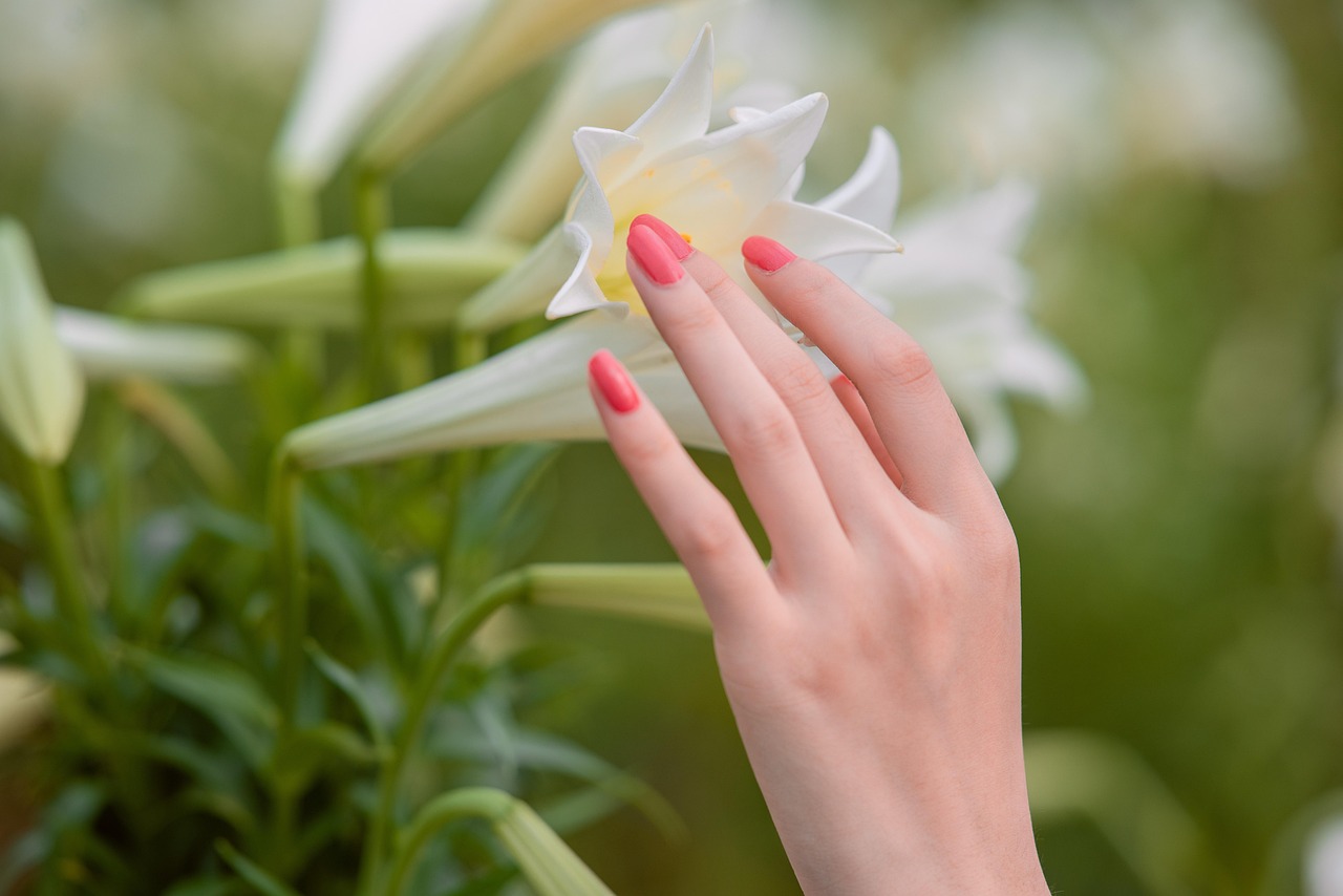 A manicured hand resting among soft flower petals